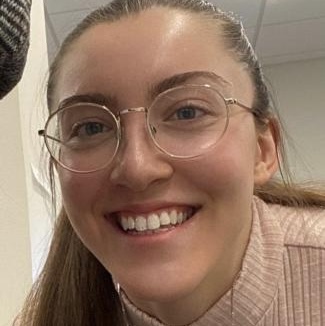 Headshot of a white woman with glasses and a long ponytail wearing a turtleneck.